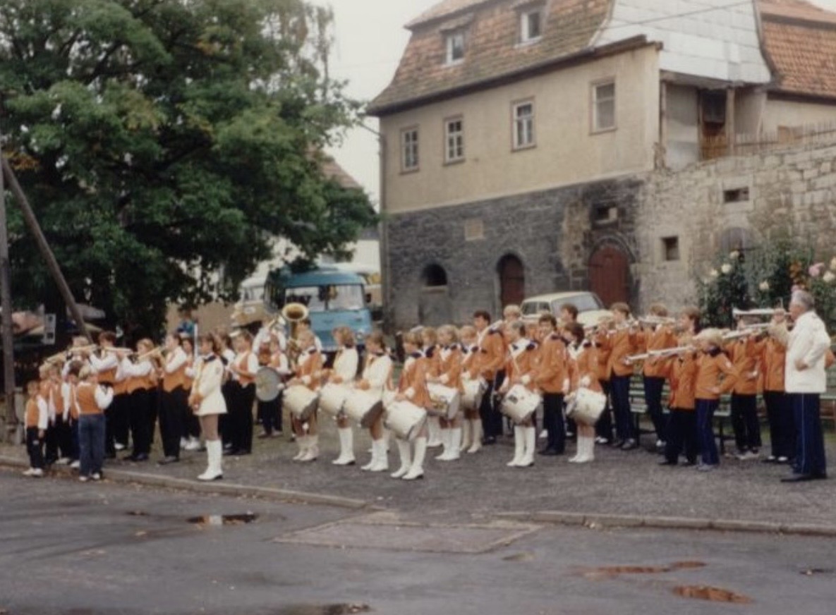 Marschkapelle in orangefarbener Uniform, Ende der 1980er Jahre
